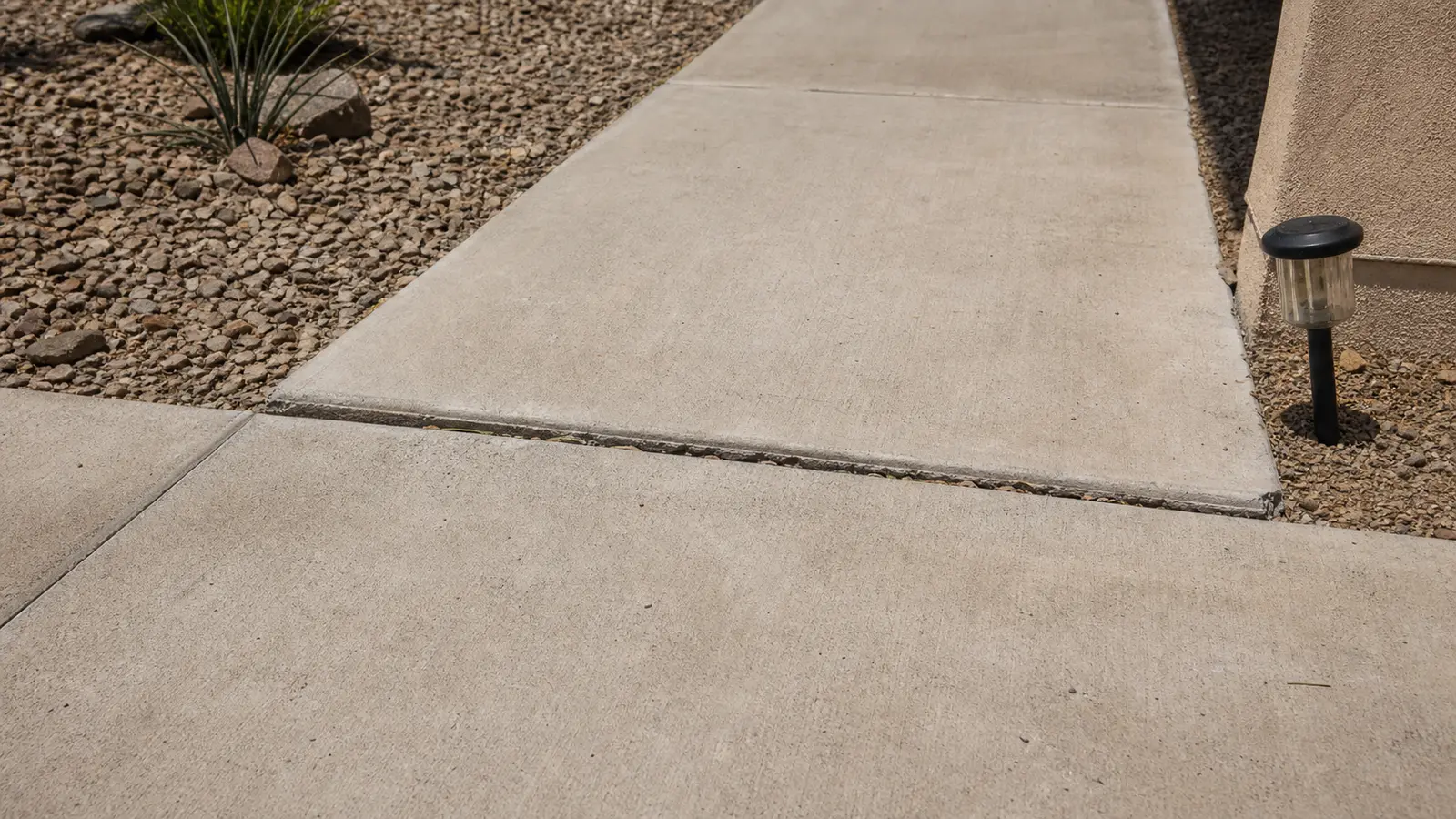 Illustrative cracked and displaced concrete walkway in a dry desert landscape, shown only for assessment context