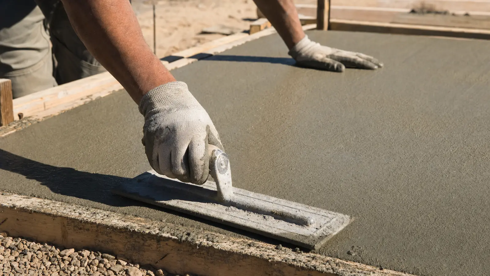 Illustrative workers finishing fresh concrete in a desert setting, shown only as process context